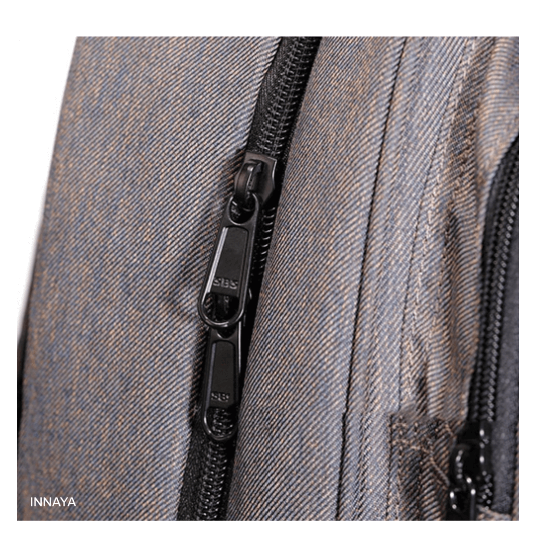 Close-up of INNAYA™ H-Backpack's durable zippers on a sleek fabric, showcasing quality design and construction.